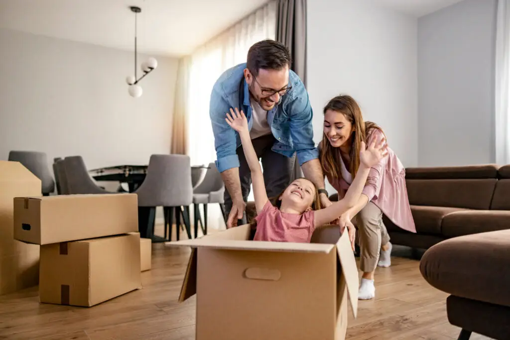 Family unpacking moving boxes in the living room of their first home